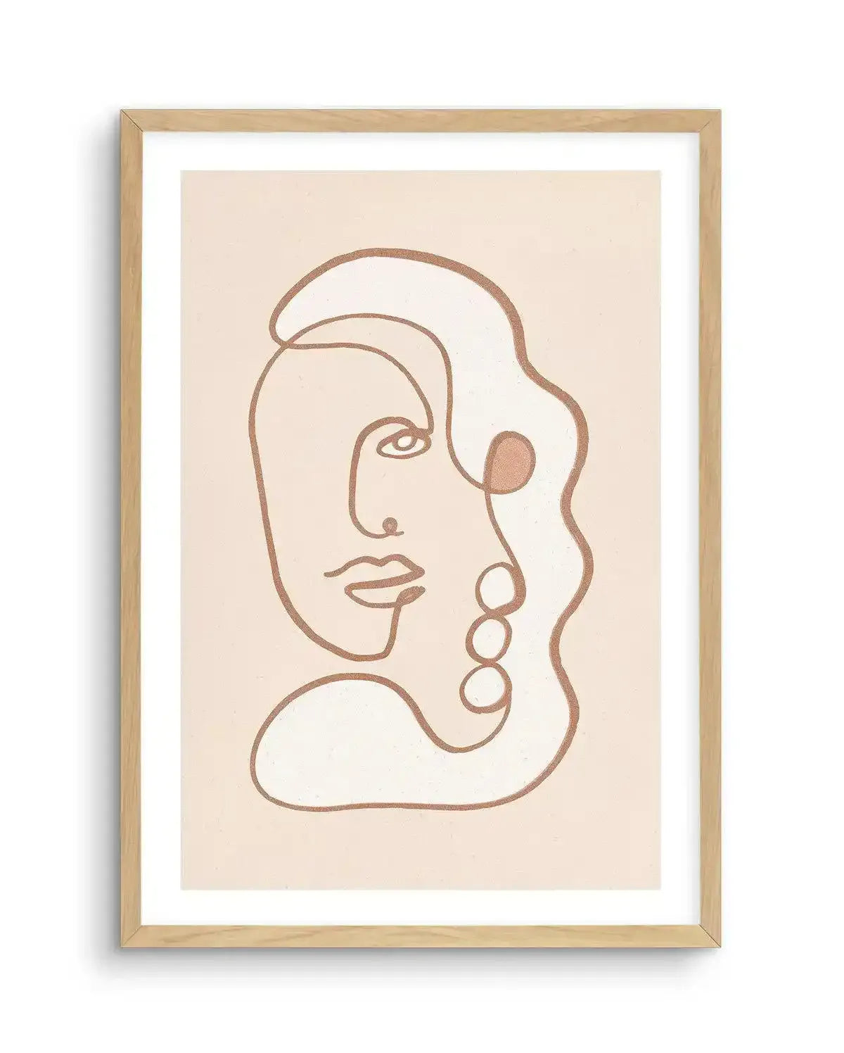 Abstract art print featuring a continuous line drawing of a stylized face in a warm, glittery bronze against a pale cream background, displayed in a natural oak frame with white border. The face is depicted in profile, with an eye, nose, and lips, and is integrated into a larger abstract shape with three circular elements on the right side.
