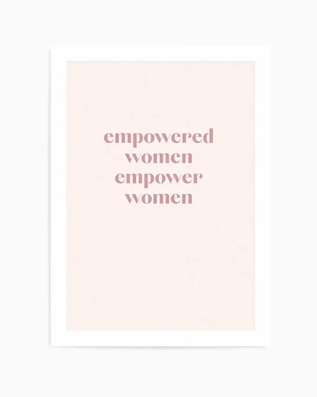 Art print featuring the phrase "empowered women empower women" in a soft, dusty rose pink, sans-serif font, centered on a pale cream background, displayed with a white border.