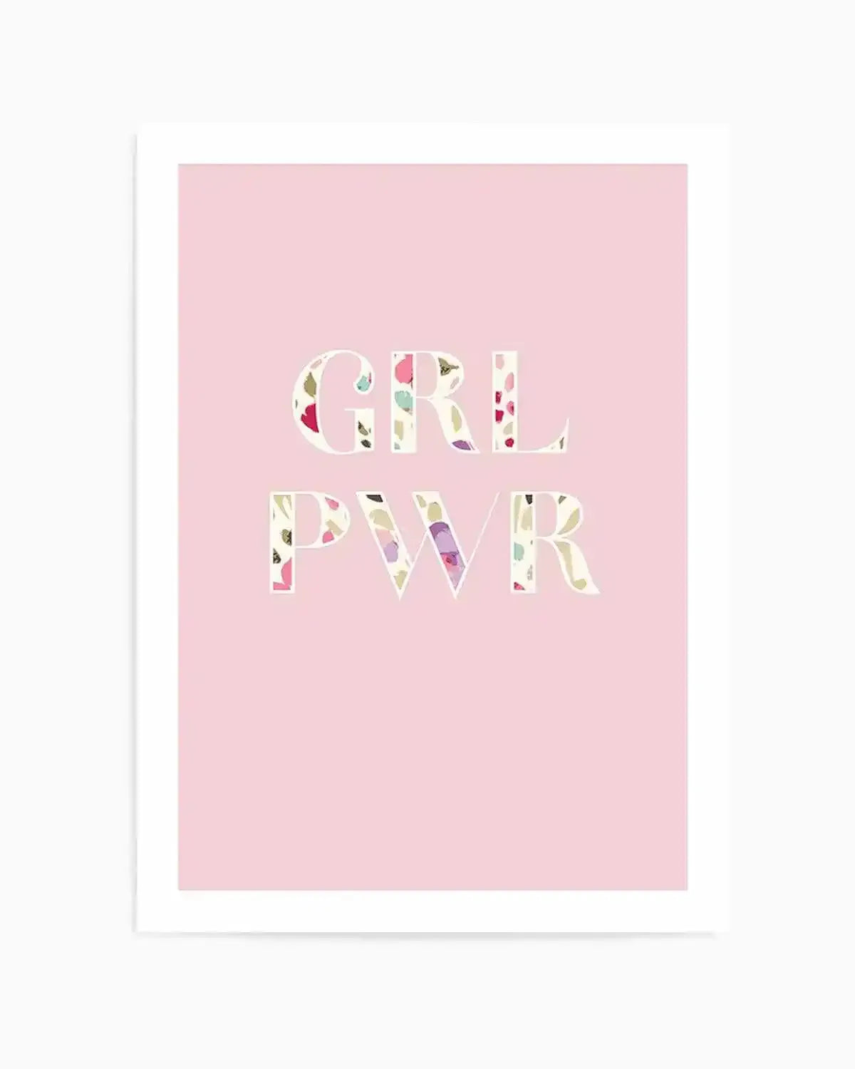 "Art print featuring the words 'GRL PWR' in large, uppercase letters with a colourful floral pattern filling each letter, set against a soft pastel pink background. The floral pattern includes small, abstract shapes in shades of pink, purple, yellow, and green, giving a watercolour-like texture. The print is displayed in a white frame with a white border."
