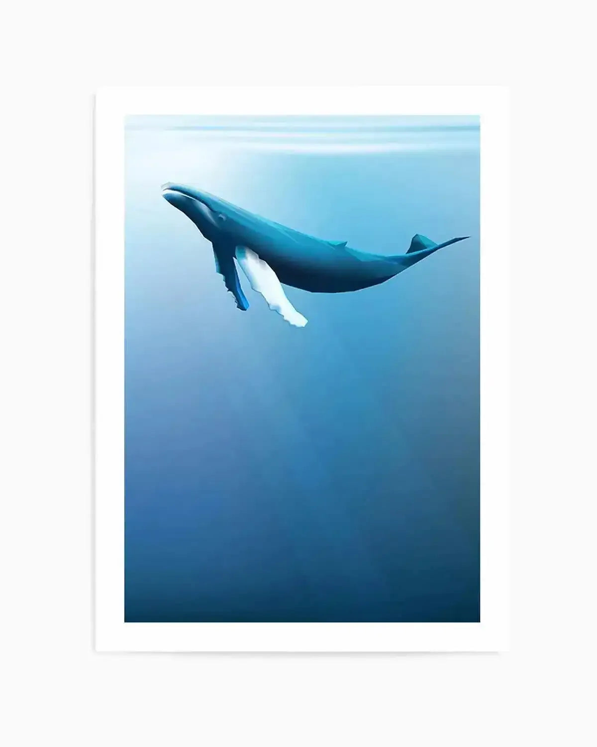Art print featuring a humpback whale swimming diagonally upward through deep blue ocean water, shown in profile. The whale's dark blue-grey body contrasts with its white pectoral fins and underbelly. The background transitions from light cyan blue at the top to deeper teal and navy blue toward the bottom, creating depth. The artwork has a serene, underwater quality rendered in soft, photorealistic illustration style. Print is displayed in a white frame with white border against a light grey background.