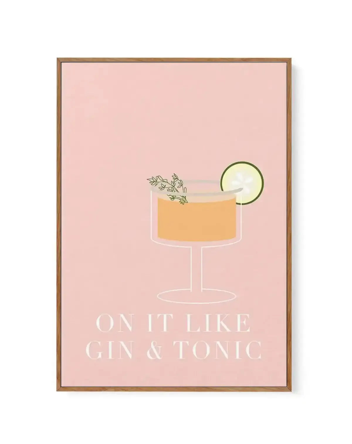 Framed canvas art print with a wooden tan frame featuring an illustrated cocktail on a blush pink background. The drink is rendered in a minimalist style with a clear coupe glass containing golden-amber liquid, garnished with a thin green lime wheel and herb sprigs. Below the illustration, white serif text reads "ON IT LIKE GIN & TONIC". The canvas has a white border around the artwork edges.