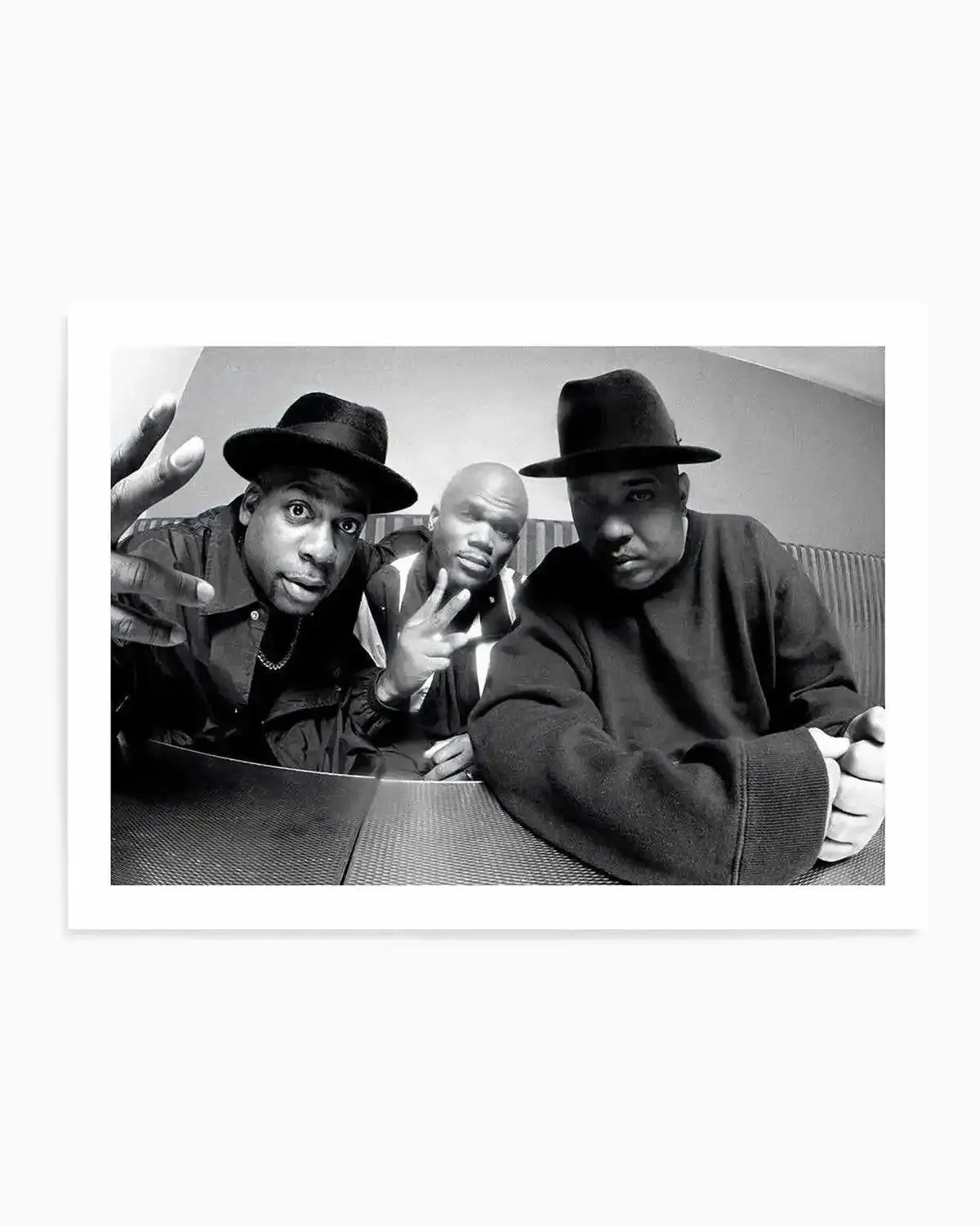 Black and white photograph art print featuring three men in fedora hats posed closely together looking directly at the camera with expressive faces. The men wear dark clothing and chains, positioned in an intimate group composition. The photograph has high contrast black and white tones with dramatic lighting. The print is displayed with a white border on white background.