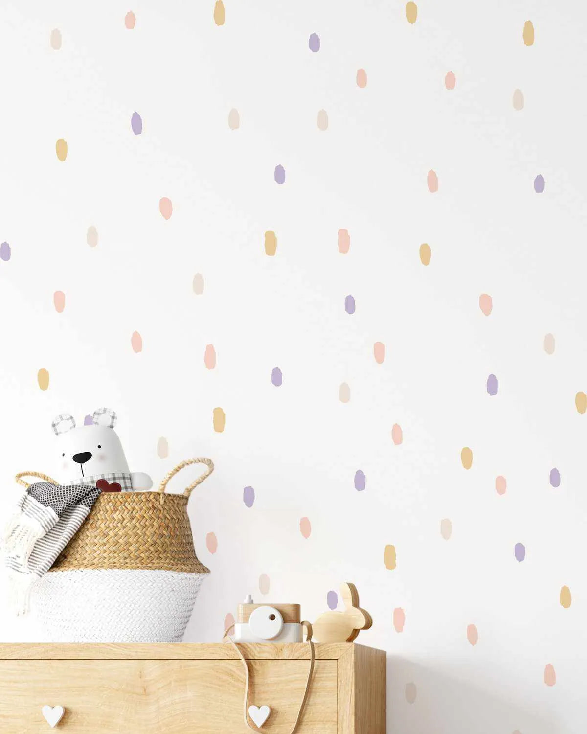 Scattered oval dot decals in pastel pink, yellow, lilac and cream on white wall in soft kids nursery