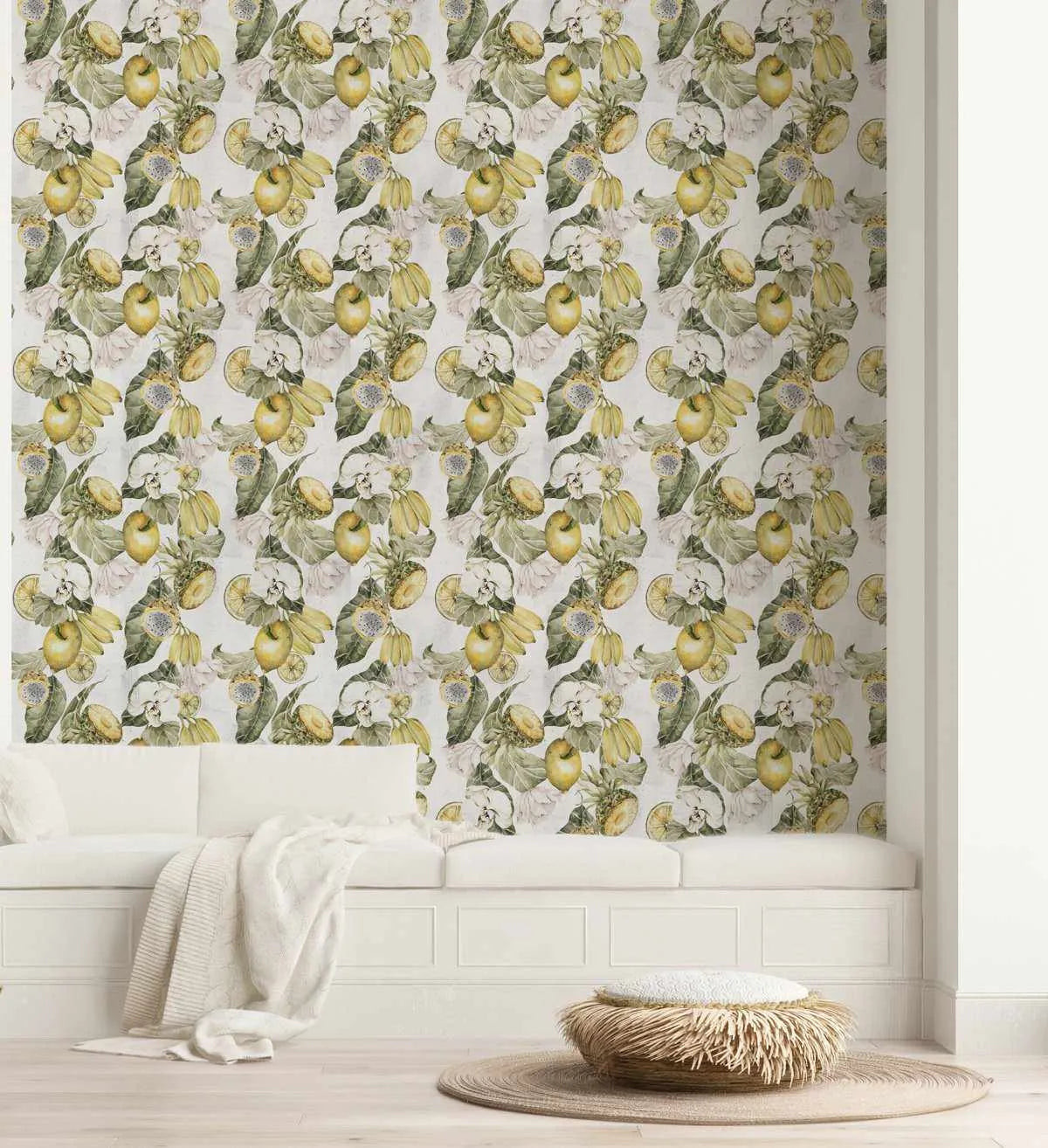 Urban Oasis Wallpaper displayed on a bathroom wall above white wainscoting. The design features a repeating botanical pattern of yellow lemons and lime slices with cream-colored blossoms and green foliage rendered in detailed watercolor illustration on a pale grey background. A white rolled towel and natural woven basket with fringe sit on a round jute rug on the floor below.