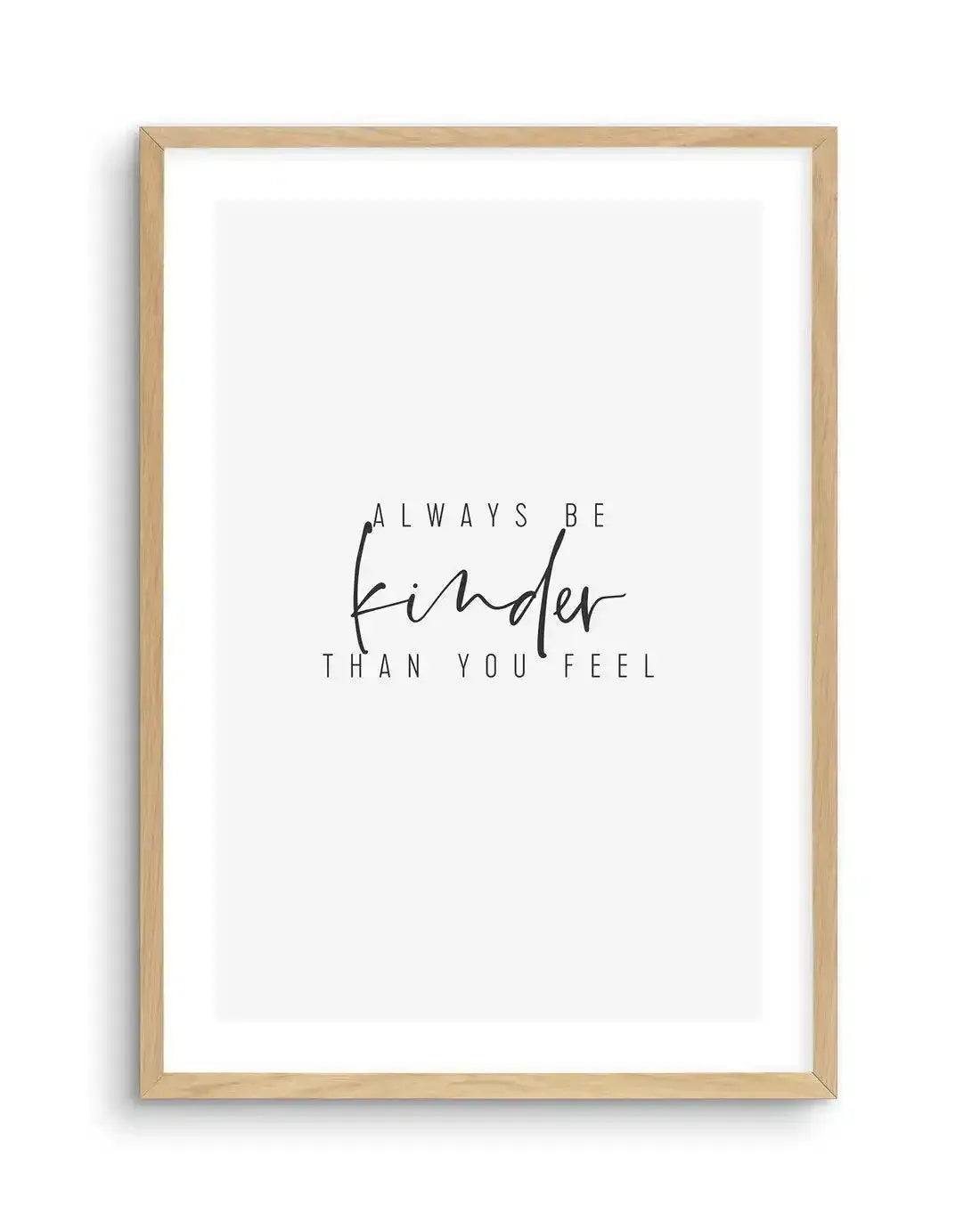 Art print featuring the phrase "ALWAYS BE kinder THAN YOU FEEL" in black text on a white background, with "kinder" in a flowing script font and the rest in a simple sans-serif font, displayed in a natural oak frame with white border.