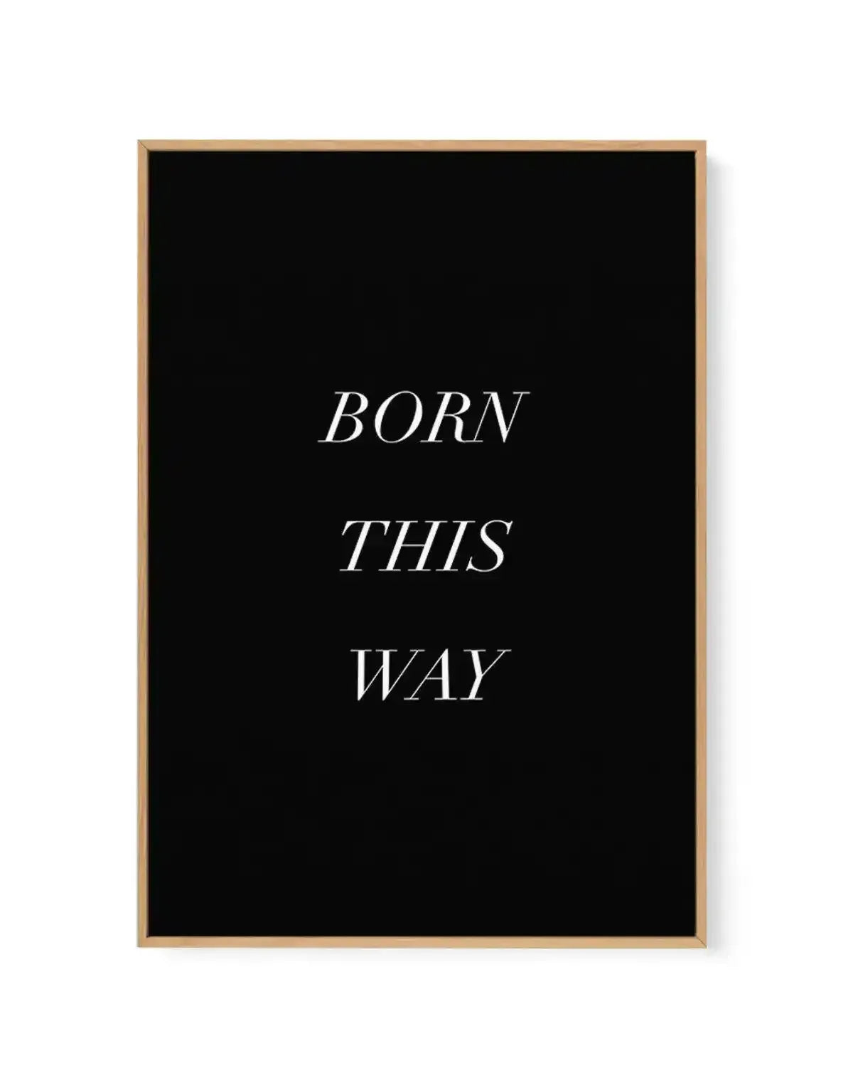 Framed canvas art print with natural wood frame displaying the phrase "BORN THIS WAY" in white italic serif typography centered on a solid black background. The canvas has a matte finish with clean, minimalist design and is shown mounted on a white wall.