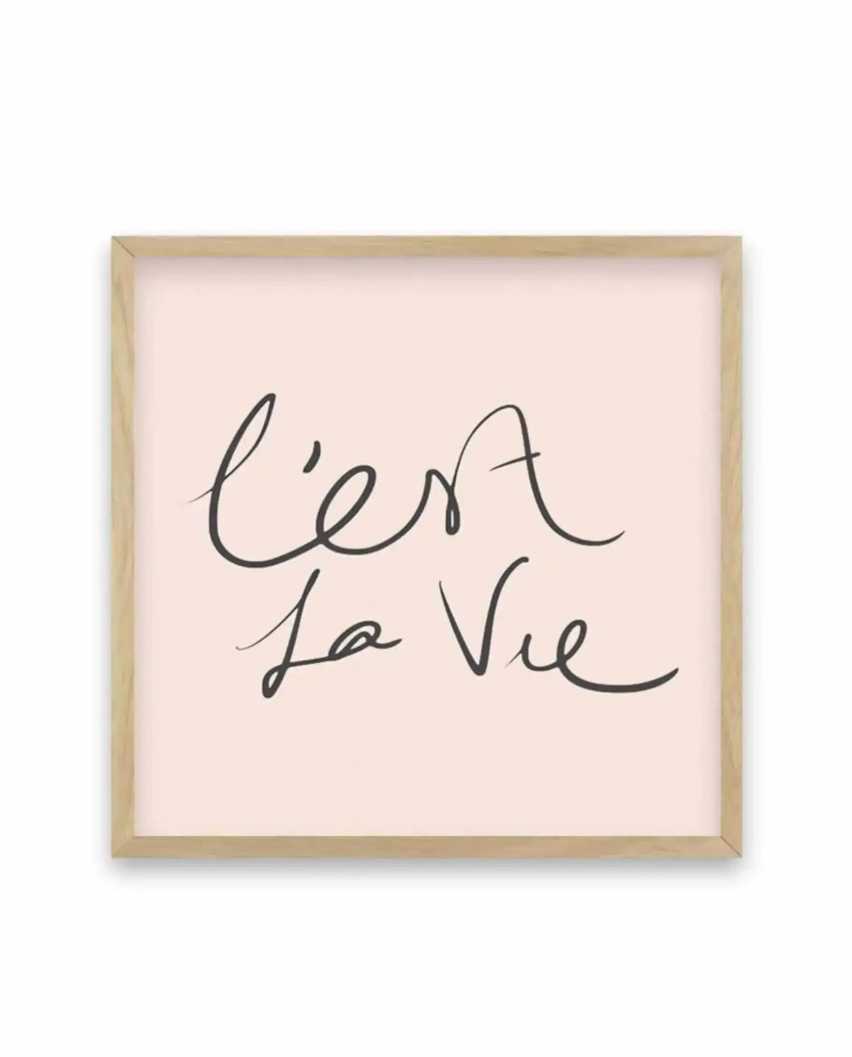 Square art print with natural wood frame featuring handwritten script text reading "C'est La Vie" in dark charcoal gray ink on a soft cream background. The cursive lettering is loose and flowing with organic line weight variations. The wooden frame has a light natural finish and is displayed against a white backdrop, showing the print's minimalist aesthetic and subtle texture of the off-white paper.