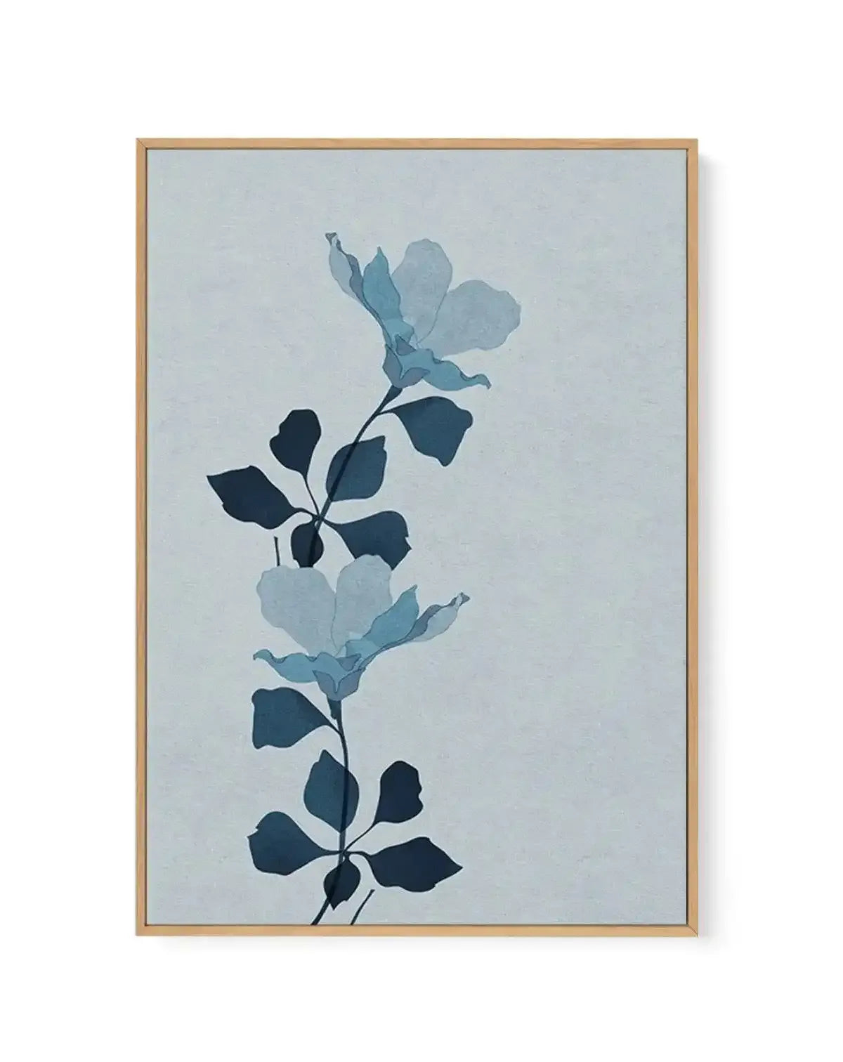 Framed canvas art print featuring an abstract botanical design with two vertical stems bearing leaves and flowers in varying shades of blue and navy against a pale blue-grey background. The composition uses a minimalist style with layered silhouettes creating depth. The artwork is displayed in a natural wood frame with a light finish. The overall aesthetic is calm and contemporary.