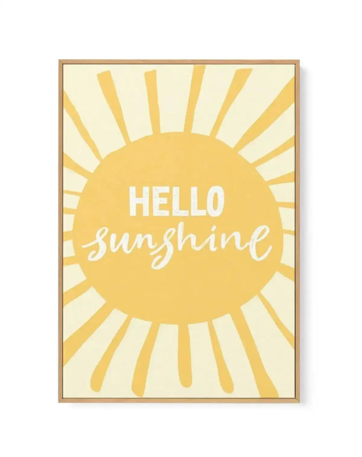 Framed canvas art print featuring a large golden-yellow sun with radiating rays in the center of a cream background. White text reads "HELLO" in sans-serif capitals above "sunshine" in flowing white script lettering, both centered on the sun. The canvas is set in a natural wood frame with a thin border.