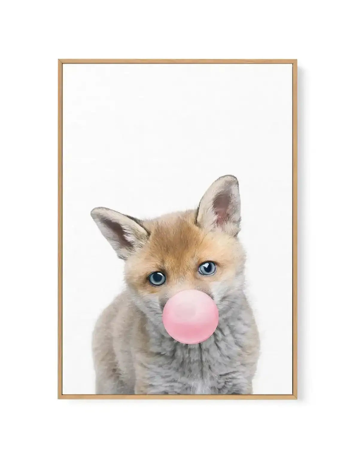 Canvas art print featuring a young fox with tan and cream colored fur and bright blue eyes, blowing a large bubble gum bubble in soft pink. The fox is centered against a clean white background, depicted in a gentle watercolor illustration style. The artwork is mounted in a natural wood frame with a white border, creating a portrait-oriented composition.