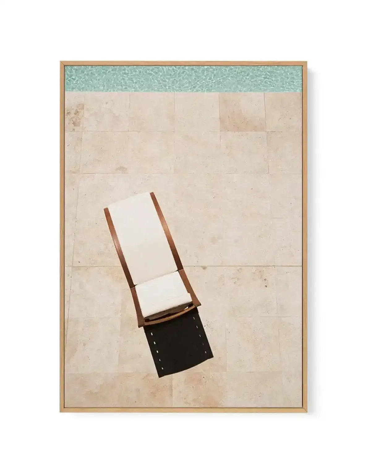 Framed canvas art print featuring an overhead view of a wooden lounge chair with white cushioning and dark seat positioned on a beige tile floor beside turquoise water, rendered in a minimalist illustration style with soft, muted tones and clean geometric shapes, displayed in a natural wood frame with white border.