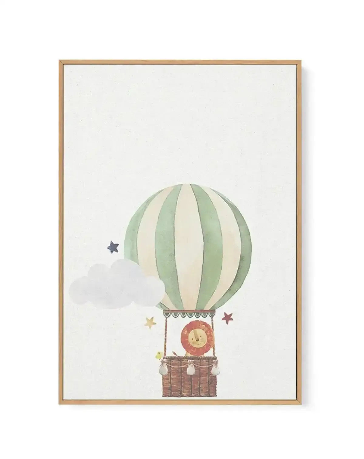 Watercolor illustration of a hot air balloon with vertical stripes in sage green and cream, suspended above a woven basket containing a cheerful lion character with a red mane. A gray cloud floats to the left, with a small dark star and two golden stars scattered nearby against a cream background. The artwork is framed in natural wood with a subtle shadow effect visible on the right edge.