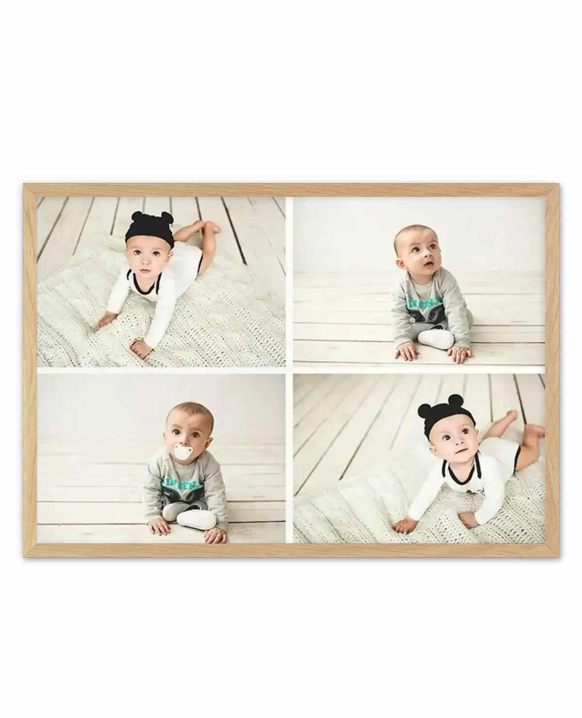 Framed photography art print featuring four individual portraits of a baby in different poses, arranged in a grid. Each photo shows the baby on a white wooden floor, with either a white knitted blanket or a plain white background. The baby wears a black bear-ear hat in two photos and a grey long-sleeved onesie in the other two, with a pacifier in one. The frame is natural oak with a white border.