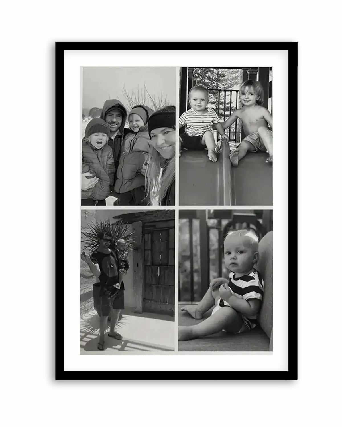 Black-framed art print displaying a 2x2 grid of four black and white photographs. Top left shows a group of adults and children bundled in winter clothing outdoors. Top right depicts two young children sitting together indoors. Bottom left captures a child holding a large decorative plant near a doorway. Bottom right is a close-up portrait of a smiling infant in striped clothing. The print has a white border and is mounted in a black wooden frame.