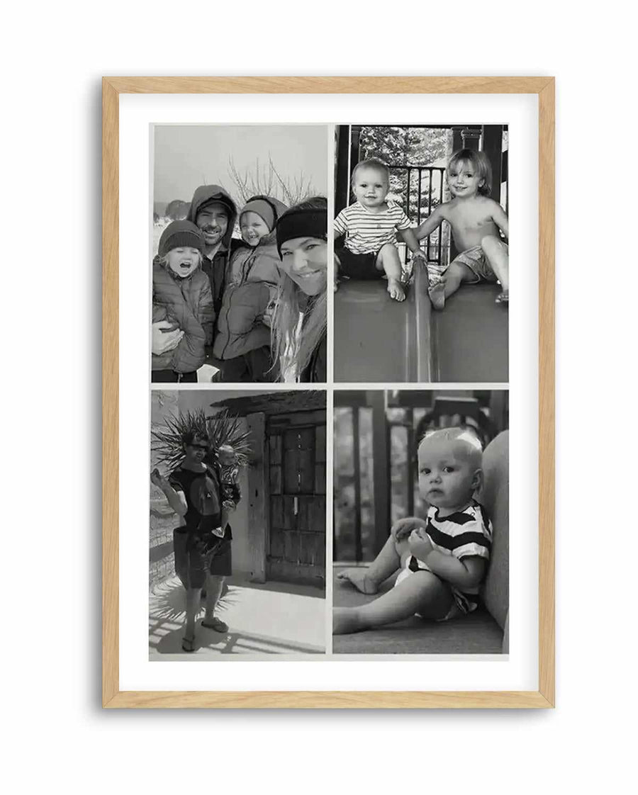 Framed black and white photography art print featuring four individual family photos arranged in a grid, displayed in a natural oak frame with white border. The top left photo shows a family of four in winter clothing, smiling. The top right photo shows two young children, one shirtless, sitting on a playground slide. The bottom left photo shows a man holding a baby outdoors. The bottom right photo shows a baby sitting on a cushion.