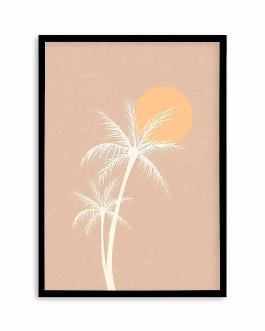 Framed art print featuring two palm trees in a minimalist illustration style against a warm, dusty pink background. The palm trees are depicted in a pale cream or off-white color, with the larger tree in the foreground and a smaller one behind it. A large, circular, pale orange sun is positioned behind the larger palm tree, partially obscured by its fronds. The overall composition evokes a serene, retro sunset beach scene. The print is displayed in a black frame with a white border.