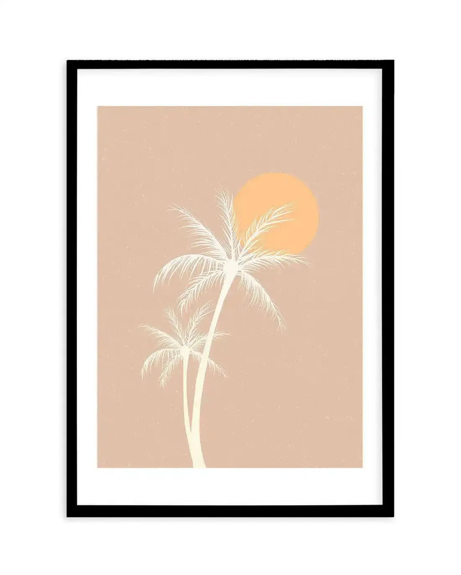 Art print featuring a minimalist illustration of two palm trees in a pale cream silhouette against a warm, dusty pink background, with a large, soft orange sun partially visible behind the taller palm. The print is displayed in a black frame with a white border.