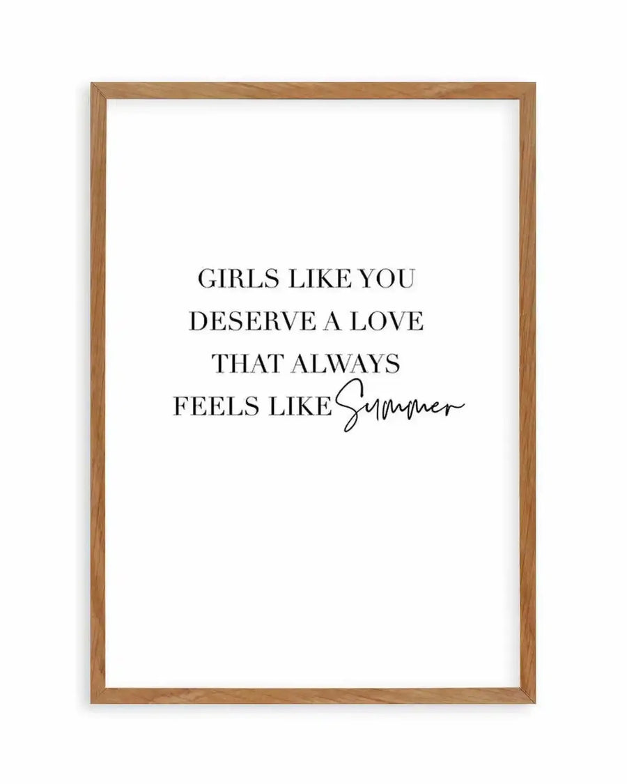 Text art print featuring the quote "GIRLS LIKE YOU DESERVE A LOVE THAT ALWAYS FEELS LIKE Summer" in black serif and script fonts on a white background, displayed in a natural oak frame with white border.