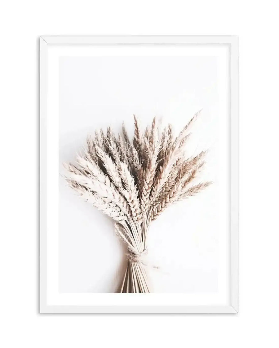 Framed art print featuring a minimalist photograph of a dried wheat bouquet tied with twine against a bright white background. The wheat stalks are a natural beige and light brown, creating a soft, rustic composition.