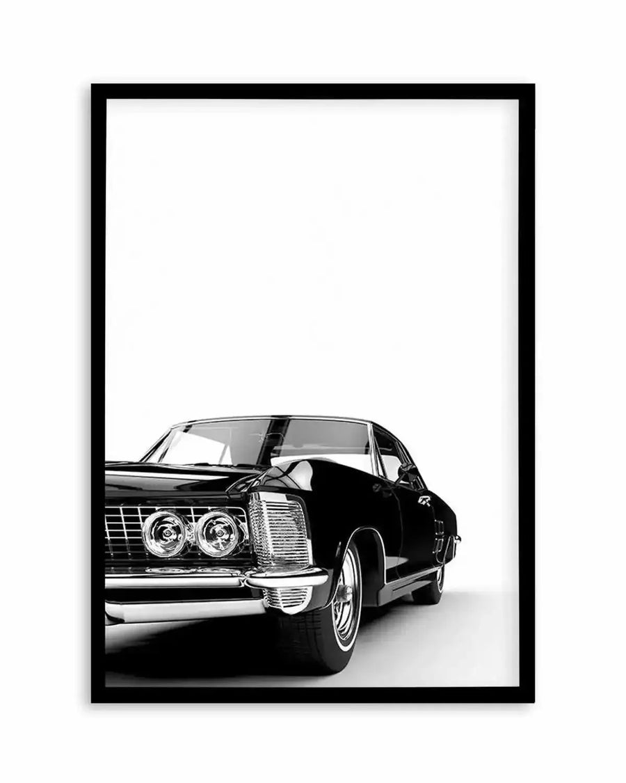 Black and white photograph of a classic American muscle car from the 1960s displayed in a black frame with white border. The vintage sedan features dual round headlights, horizontal grille slats, and a sleek side profile with the door open. The car is positioned against a plain white background, emphasizing its chrome details and curved bodywork. The framed print is mounted on a white wall.