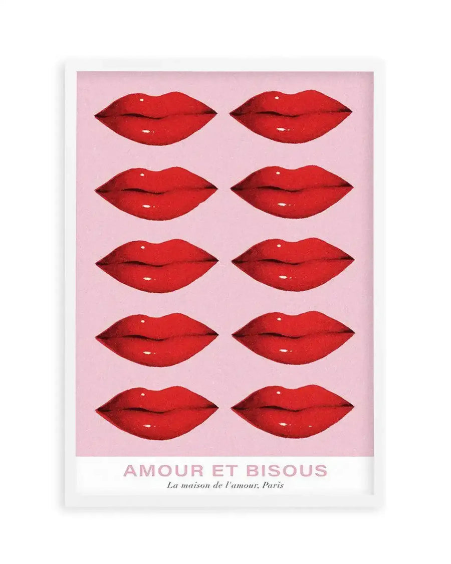 Art print featuring ten pairs of glossy red lips arranged in five rows of two on a soft pink background. The illustration has a slightly textured, almost grainy finish, and the lips are depicted with subtle highlights to suggest shine. The print is displayed in a white frame with a white border, and at the bottom, the text "AMOUR ET BISOUS" is written in pink, with "La maison de l'amour, Paris" in a smaller font below it.