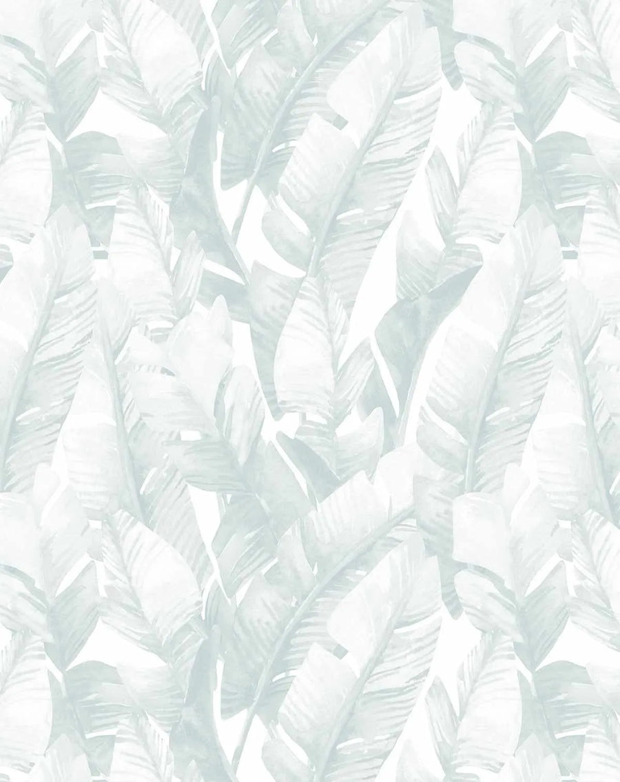 Seafoam Wallpaper with an allover repeating pattern of overlapping banana leaf palms in soft sage green and white. The leaves are rendered in a painterly watercolor style with organic brushstrokes and varying opacity, creating a layered, botanical design. The composition features diagonal movement across a light cream background, giving an airy, tropical aesthetic with subtle depth and dimension throughout.
