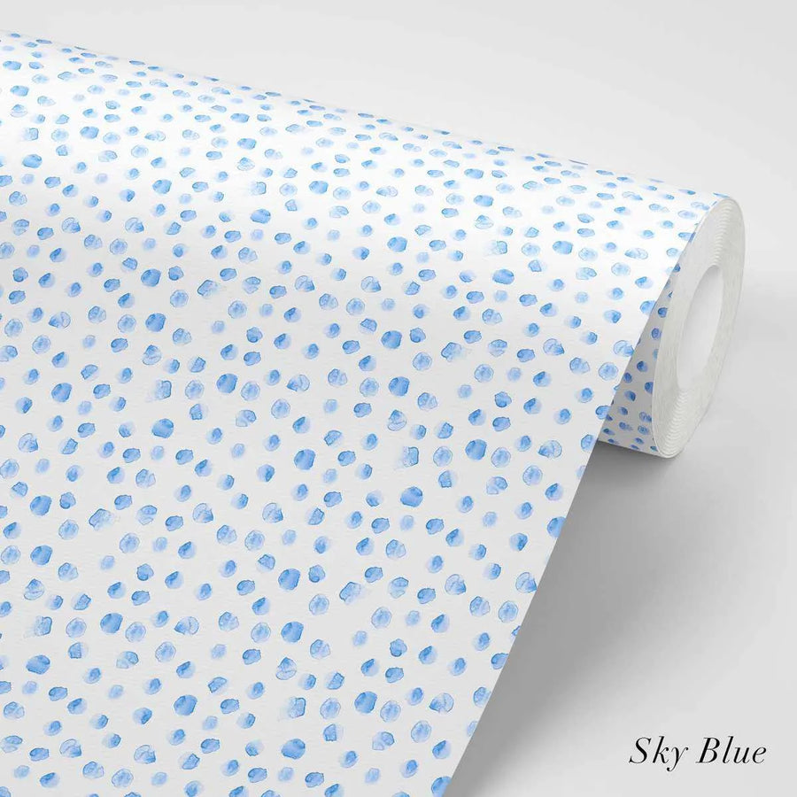 Peel and stick wallpaper featuring a repeating pattern of small, irregular, hand-painted dots in sky blue on a white background. The dots have a loose, organic watercolor quality with visible brushstroke texture.