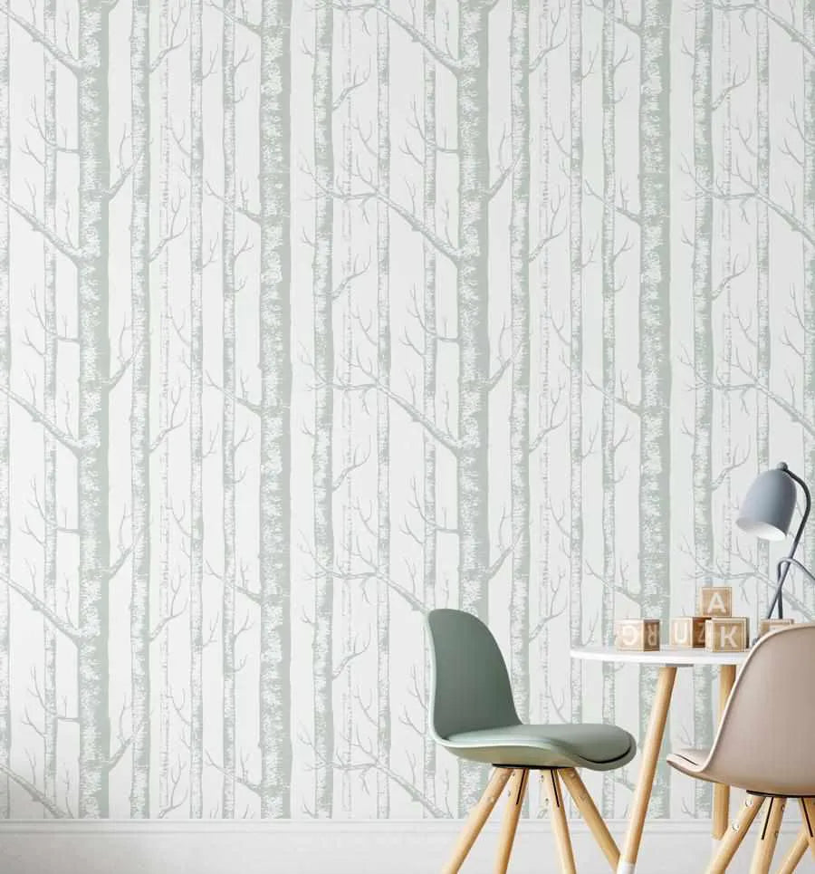 Children's Room:
"Wallpaper featuring a repeating pattern of tall, slender birch trees with delicate branches in a muted sage green and white, creating a serene forest scene. The wallpaper covers a wall in a bright room, with a small white round table and two modern chairs in sage green and beige in the foreground. Building blocks with letters are stacked on the table next to a grey desk lamp."