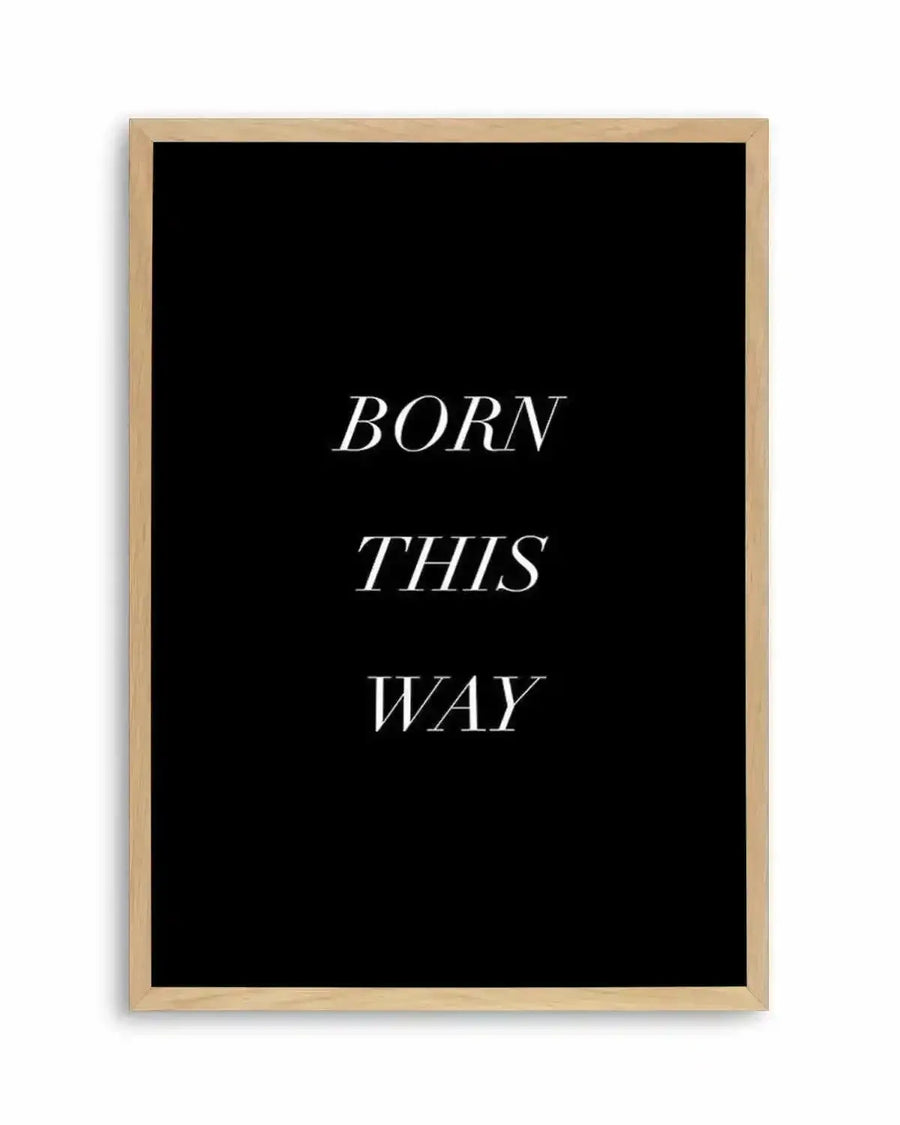 "Text-based art print featuring the words 'BORN THIS WAY' in three lines of white serif font on a solid black background, displayed in a natural oak frame with white border."