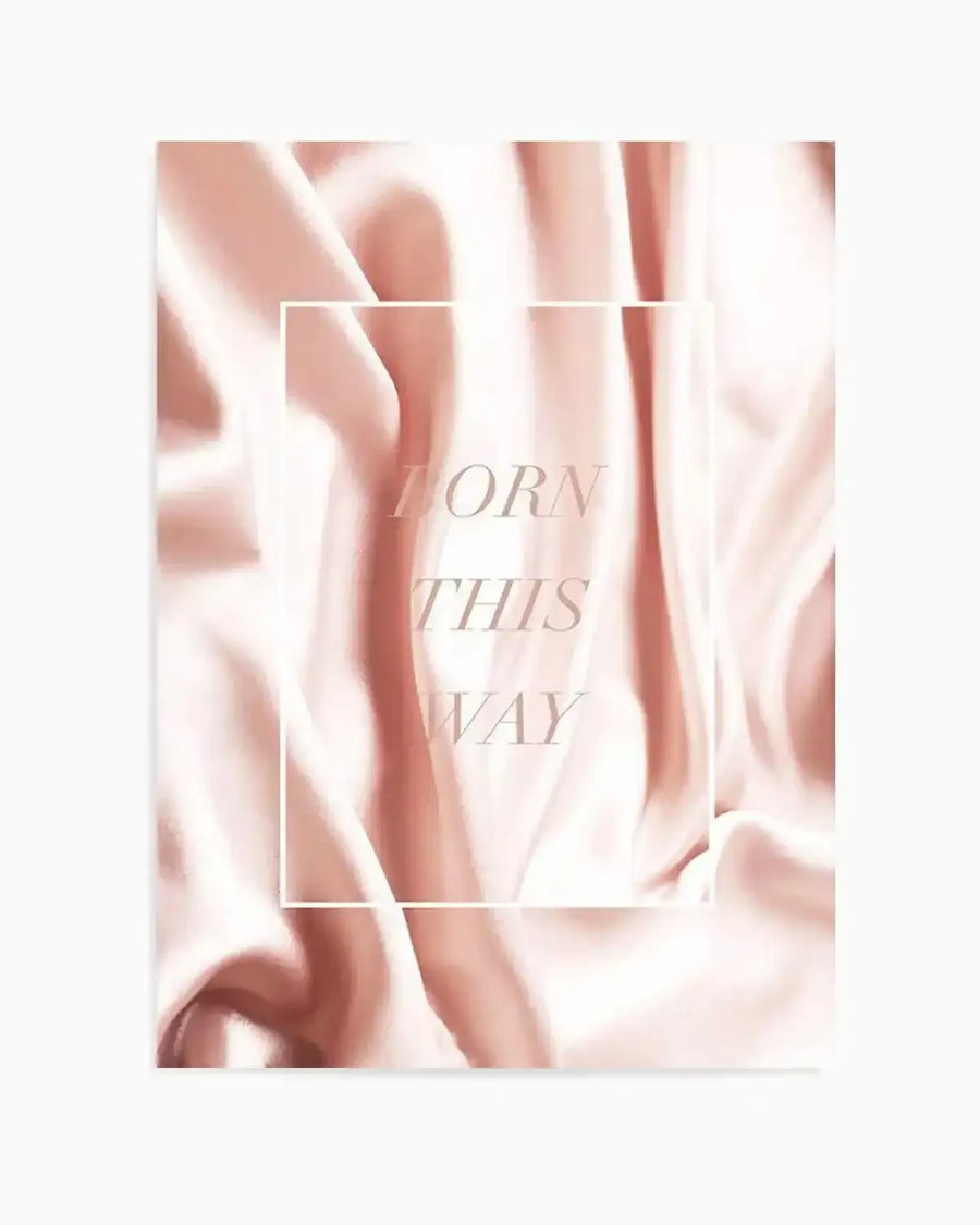 Art print featuring a soft, abstract composition of flowing, draped fabric in shades of blush pink and cream, creating gentle folds and highlights. The text "BORN THIS WAY" is centrally placed in a light, elegant serif font, enclosed within a thin white rectangular border.