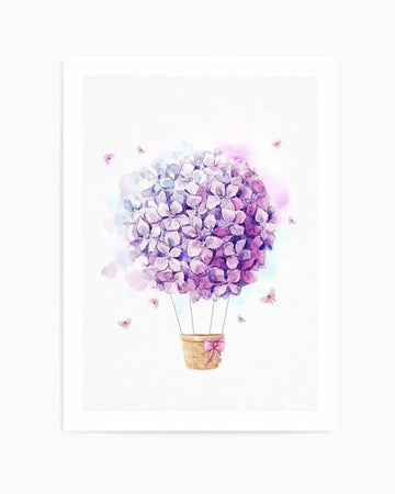 Watercolor illustration of a hot air balloon made from a large spherical cluster of purple and lavender hydrangea flowers in varying tones, suspended above a woven basket with a pink ribbon bow. Small delicate flowers float around the balloon against a soft white background with subtle blue and pink watercolor washes. The artwork is printed on linen and mounted on white board with a white border.
