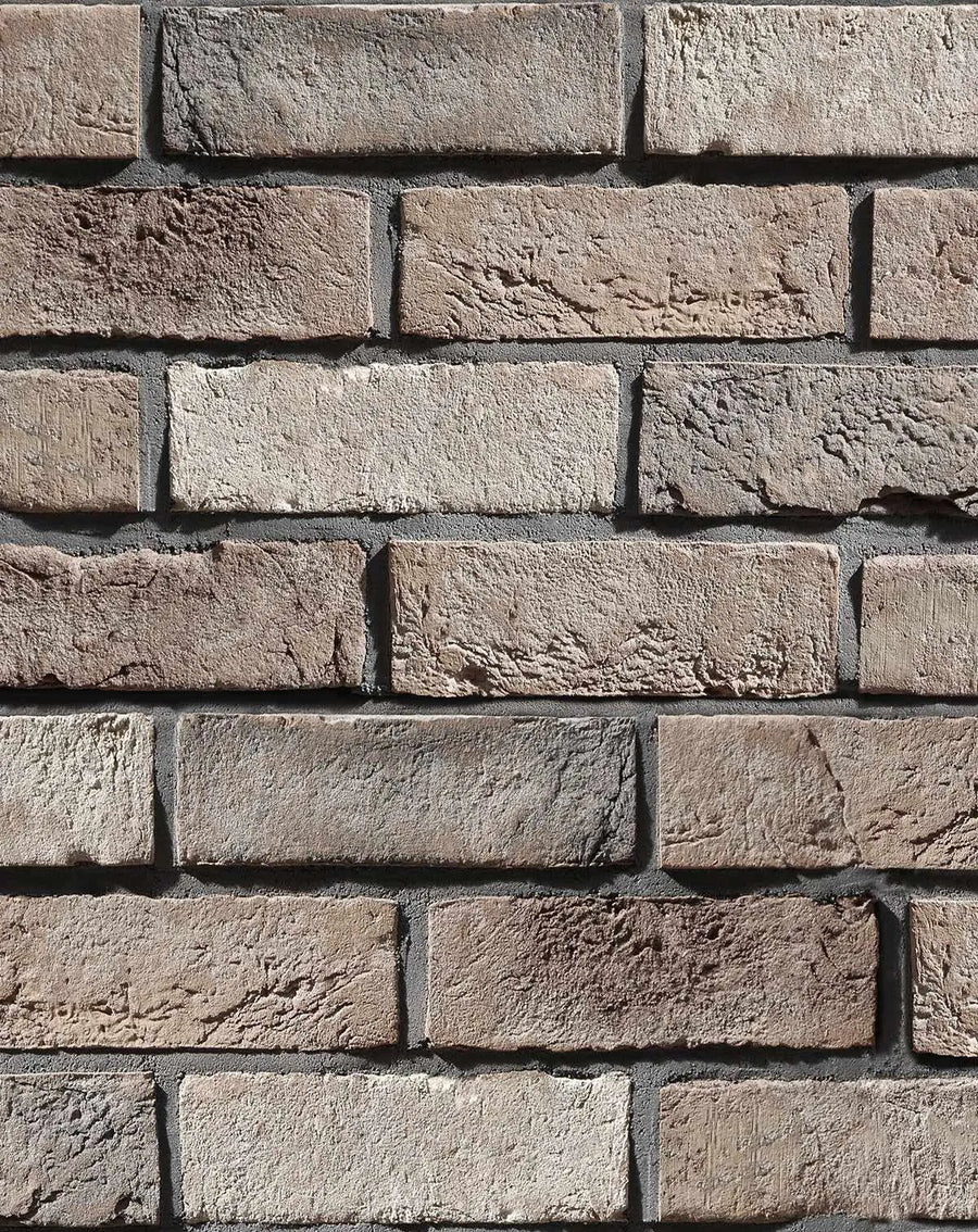 Peel and stick wallpaper featuring a repeating pattern of realistic brown bricks with varied textures and shades. The bricks range from light beige and pale grey to warm reddish-brown and dark charcoal, with visible rough, porous surfaces and irregular edges, set with dark grey mortar lines.