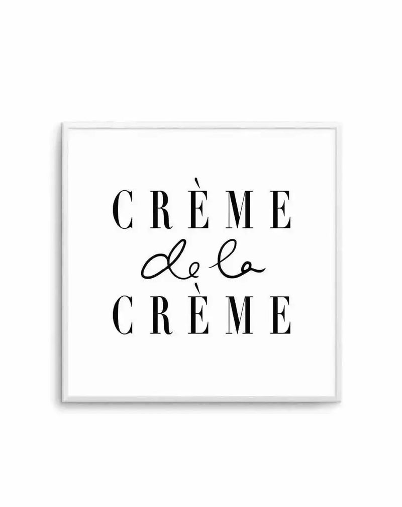 Square art print with white frame featuring elegant typography. The design displays "CRÈME DE LA CRÈME" in black serif capitals with a delicate script "de la" in cursive connecting the two phrases. Clean white background with minimalist composition. Frame appears to be light gray or silver-toned with a subtle shadow effect against white backdrop.