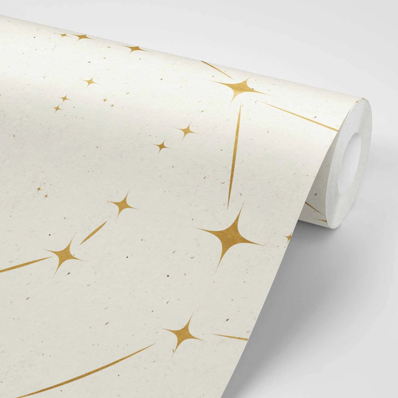 "Peel and stick wallpaper featuring a repeating pattern of gold celestial stars with radiating lines on a textured cream background. The stars have a metallic sheen and vary in size, creating a scattered, constellation-like design."