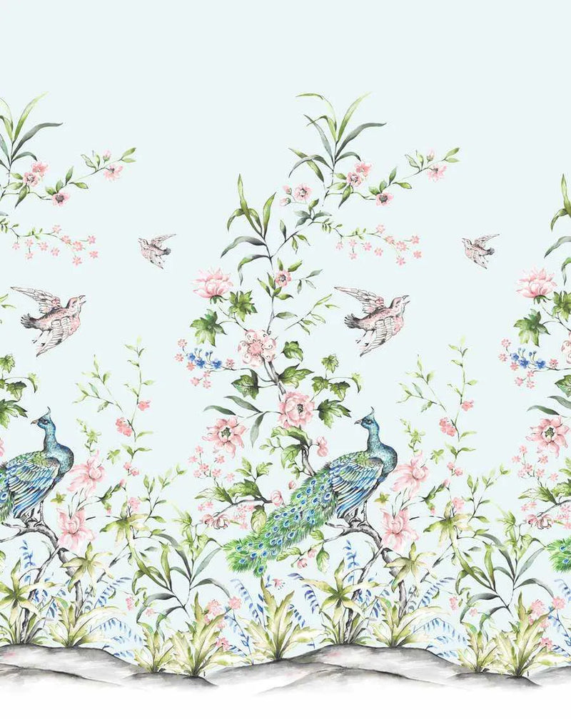 Peel and stick wallpaper featuring a repeating Chinoiserie pattern of hand-painted peacocks, birds, and blooming branches on a light blue background. The design includes two peacocks with vibrant blue and green feathers perched on branches, surrounded by delicate pink and blue flowers, green leaves, and flying birds. The bottom of the pattern shows a subtle grey and white ground with varied foliage.
