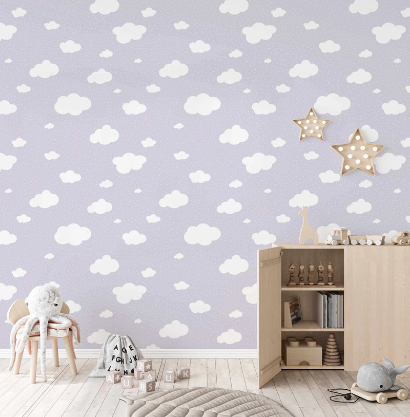 "Peel and stick wallpaper featuring a repeating pattern of white cartoon-style clouds of varying sizes and small white polka dots on a soft lilac background. The design has a whimsical, dreamy quality."