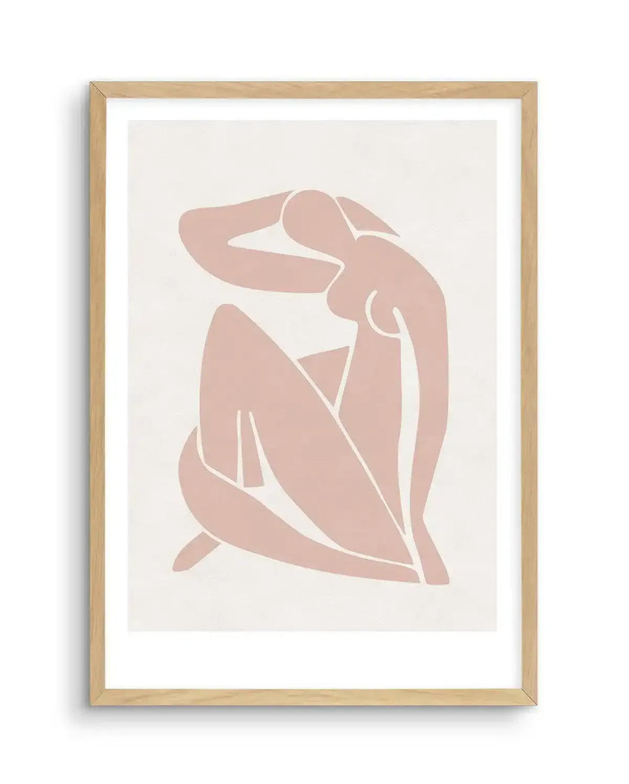 Art print featuring a minimalist illustration of a seated female figure in a muted blush pink hue with white outlines, on a cream background, printed on fine art paper and displayed in a natural oak frame with white border.