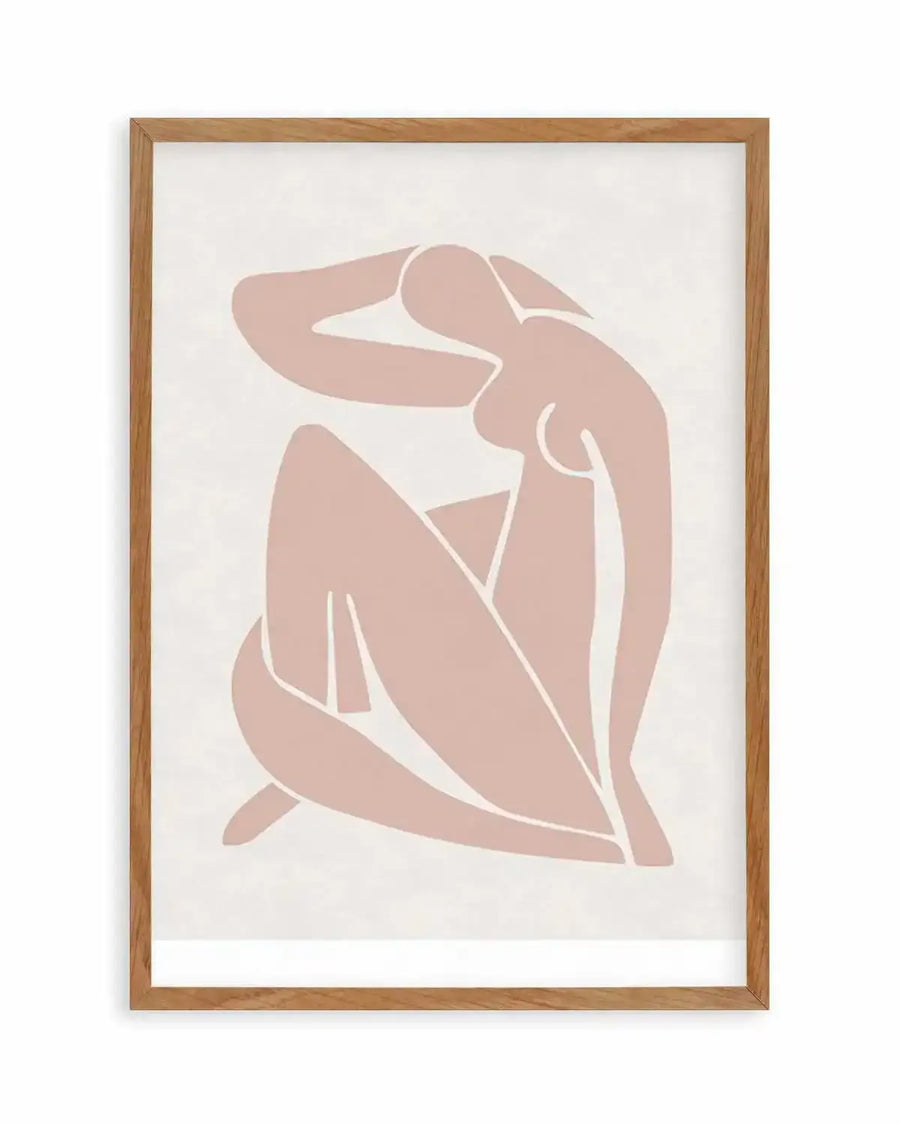 Art print featuring a minimalist abstract illustration of a seated female figure in a dusty rose hue on a cream background, displayed in a natural oak frame with white border. The figure is rendered in solid blocks of colour with white lines defining limbs and curves, with one arm raised behind her head and legs drawn up.