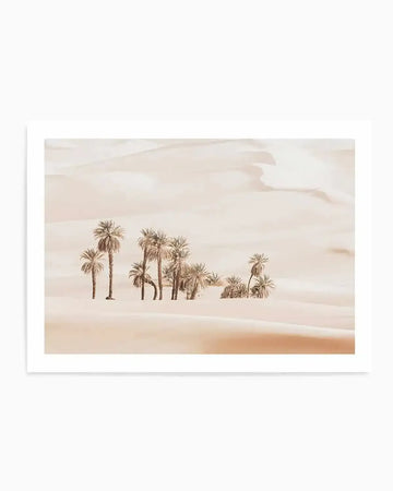 Photography art print featuring a desert oasis scene with numerous palm trees scattered across rolling sand dunes under a soft, hazy sky. The image is rendered in warm, muted tones of sandy beige, pale peach, and soft cream, creating a serene and minimalist composition. The print is displayed with a white border.