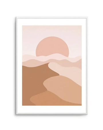 Art print featuring an abstract desert landscape with rolling sand dunes in varying shades of warm brown, tan, and beige, under a large, soft pink sun setting in a pale pink sky, displayed in a white frame with a white border.