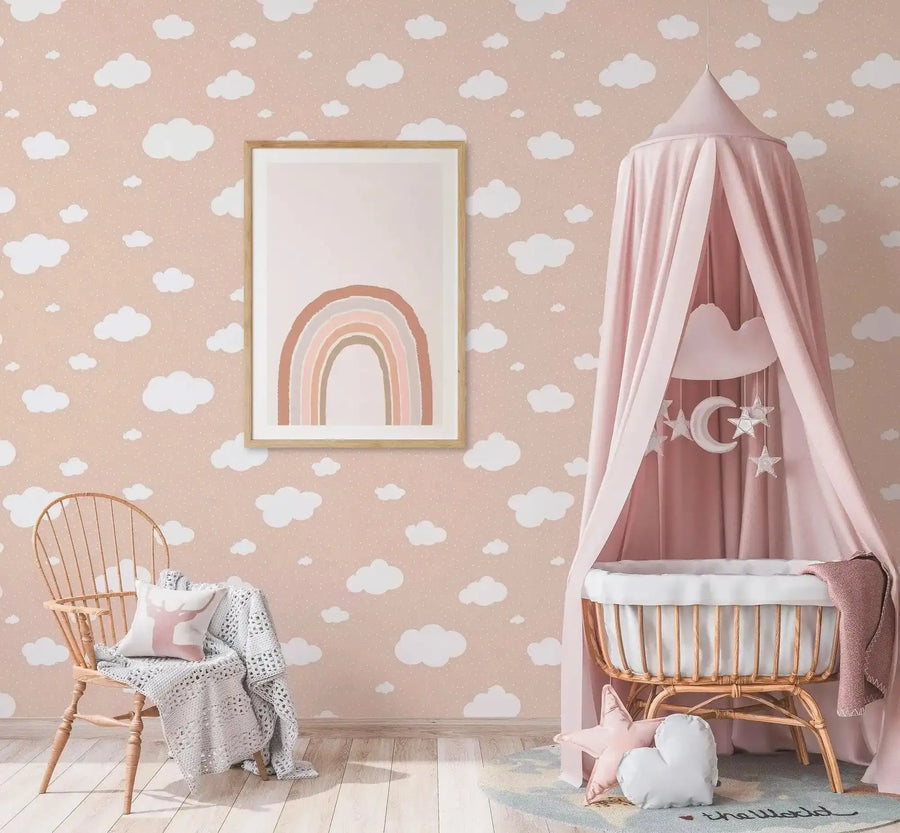 Earth's Rainbow PT Art Print displayed in a natural wood frame with white border, hung on a dusty rose wall featuring a white cloud pattern. The artwork shows a soft, hand-drawn rainbow in terracotta, peach, cream, and sage green tones on a white background. The print is styled in a nursery setting with a wicker chair, pink canopy crib with moon and star mobile, and cream knit blanket, creating a soft, calming aesthetic.