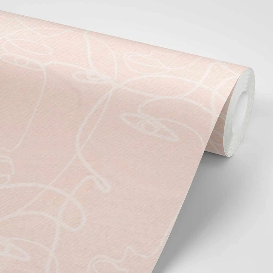Peel and stick wallpaper featuring a repeating pattern of abstract line art faces in white on a soft, muted pink background. The design has a hand-drawn, continuous line quality with subtle texture visible on the wallpaper surface.