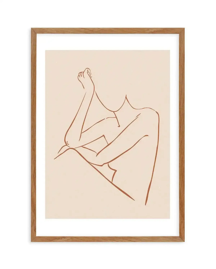 Line art print featuring a minimalist illustration of a female form in a seated pose, rendered in a single terracotta-brown line on a cream background, printed on fine art paper and displayed in a natural oak frame with white border.