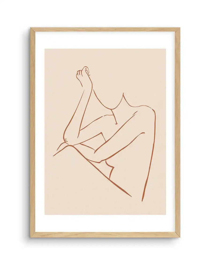 Line art print featuring a minimalist female form in a relaxed pose, with arms crossed and head tilted, rendered in a single terracotta-coloured line on a cream background, printed on fine art paper and displayed in a natural oak frame with white border.