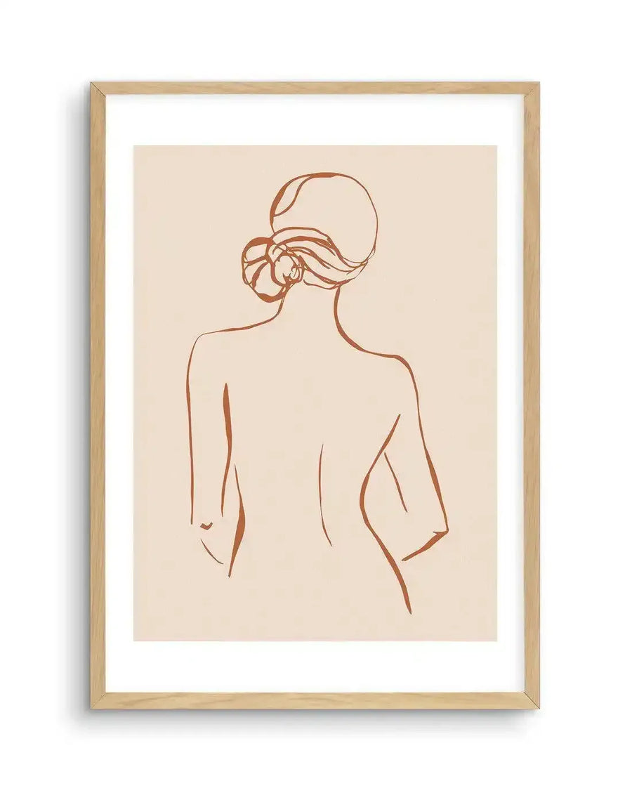 Line art print featuring a minimalist illustration of a female form from the back, with hair styled in a bun, rendered in a single terracotta-brown line on a warm cream background, printed on fine art paper and displayed in a natural oak frame with white border.