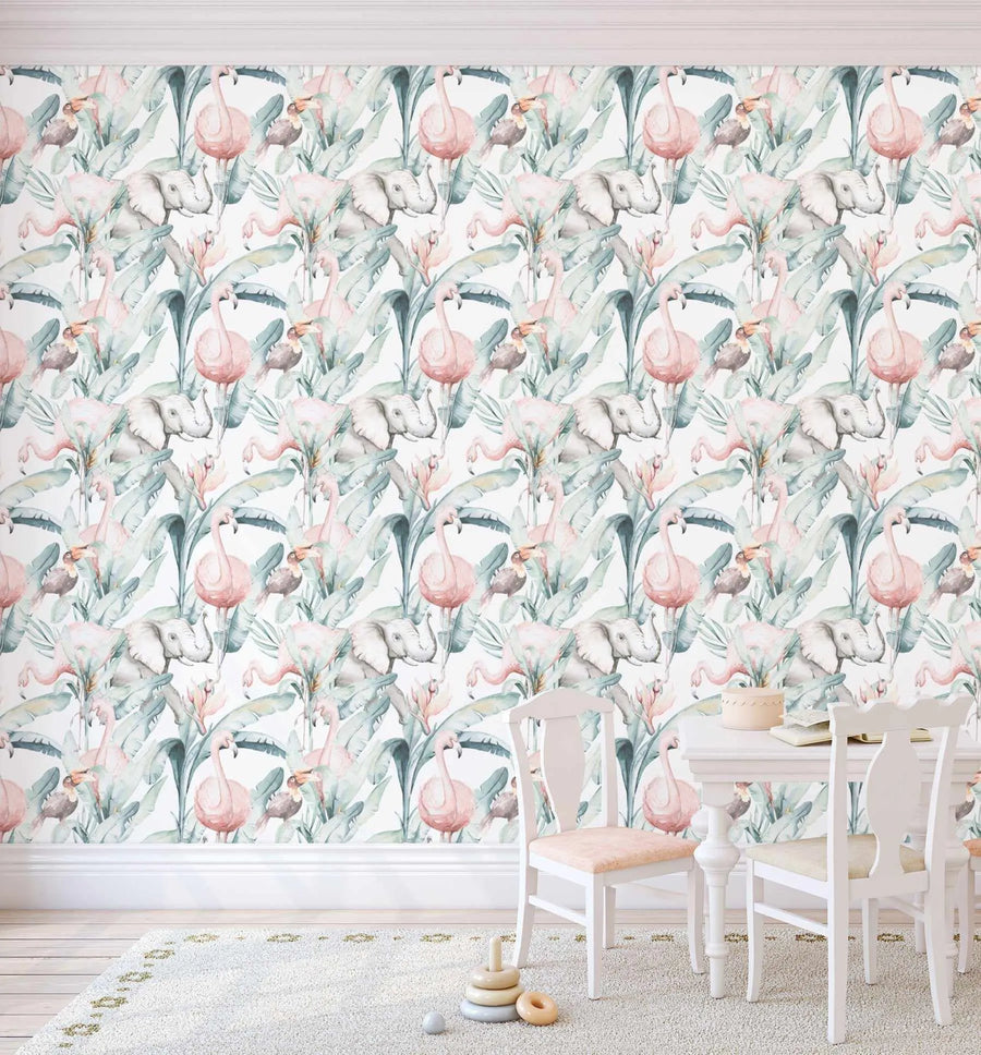 Children's Room:
"Peel and stick wallpaper featuring a repeating pattern of hand-painted flamingos, elephants, and toucans amidst tropical palm leaves and flowers in soft pink, muted grey, and sage green on a white background. The wallpaper is displayed in a child's room with white wainscoting, a light wood floor, and a cream rug. A white table and two white chairs with light pink cushions are in the foreground, along with wooden stacking toys."