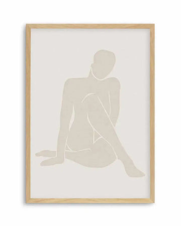 Framed art print featuring a minimalist line drawing of a seated female figure in soft beige tones against a cream background. The figure is rendered as a simplified silhouette with delicate white line work defining the body's contours and posture. The figure sits with one leg extended and one bent, head turned slightly. Natural wood frame with white border surrounding the artwork on cream-colored paper. Understated, contemporary aesthetic with neutral color palette.