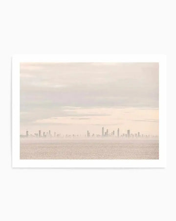 Product shot of a photography art print featuring a hazy, muted landscape of a distant city skyline across a calm body of water, under an overcast sky. The colour palette is soft and desaturated, with pale peach, light grey, and cream tones, creating a serene and atmospheric mood.
