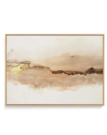 Framed canvas art print featuring an abstract landscape in warm earth tones. The composition shows layered horizontal brushstrokes in cream, beige, tan, and brown with metallic gold leaf accents along the upper left and center ridge. The painted elements create a misty, atmospheric effect suggesting rolling hills or terrain. The canvas is mounted in a natural wood frame with a white border, displayed against a neutral background.