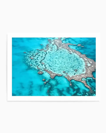 Aerial photography art print of the Great Barrier Reef, featuring a vast expanse of turquoise and deep blue ocean with intricate coral formations visible beneath the surface. The composition highlights the varied depths and vibrant colours of the reef, with lighter aqua areas indicating shallow waters and darker blues representing deeper sections.